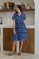 Woman poses in a 100% cotton navy blue base floral print relaxed fit collared short sleeve dress.