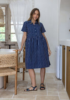 Woman wearing a 100% cotton navy blue base white striped print relaxed fit collared short sleeve dress.