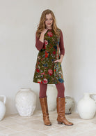 Woman wearing a moss green based multi-coloured floral print cotton velvet sleeveless tunic with pockets and side zip