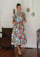 Woman wearing a 1950's style short sleeved, button through cotton dress and high round neckline with hands in pocket
