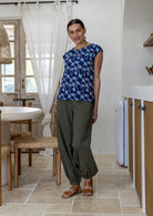 Woman wears 100% cotton top in navy based floral print with cap sleeves paired with plain pants