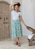 Woman wearing a basic white top and sage green floral a-line cotton skirt with side zipper 