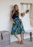 Model wearing 100% cotton knee length A-line skirt with side zipper and pockets in navy blue based floral print