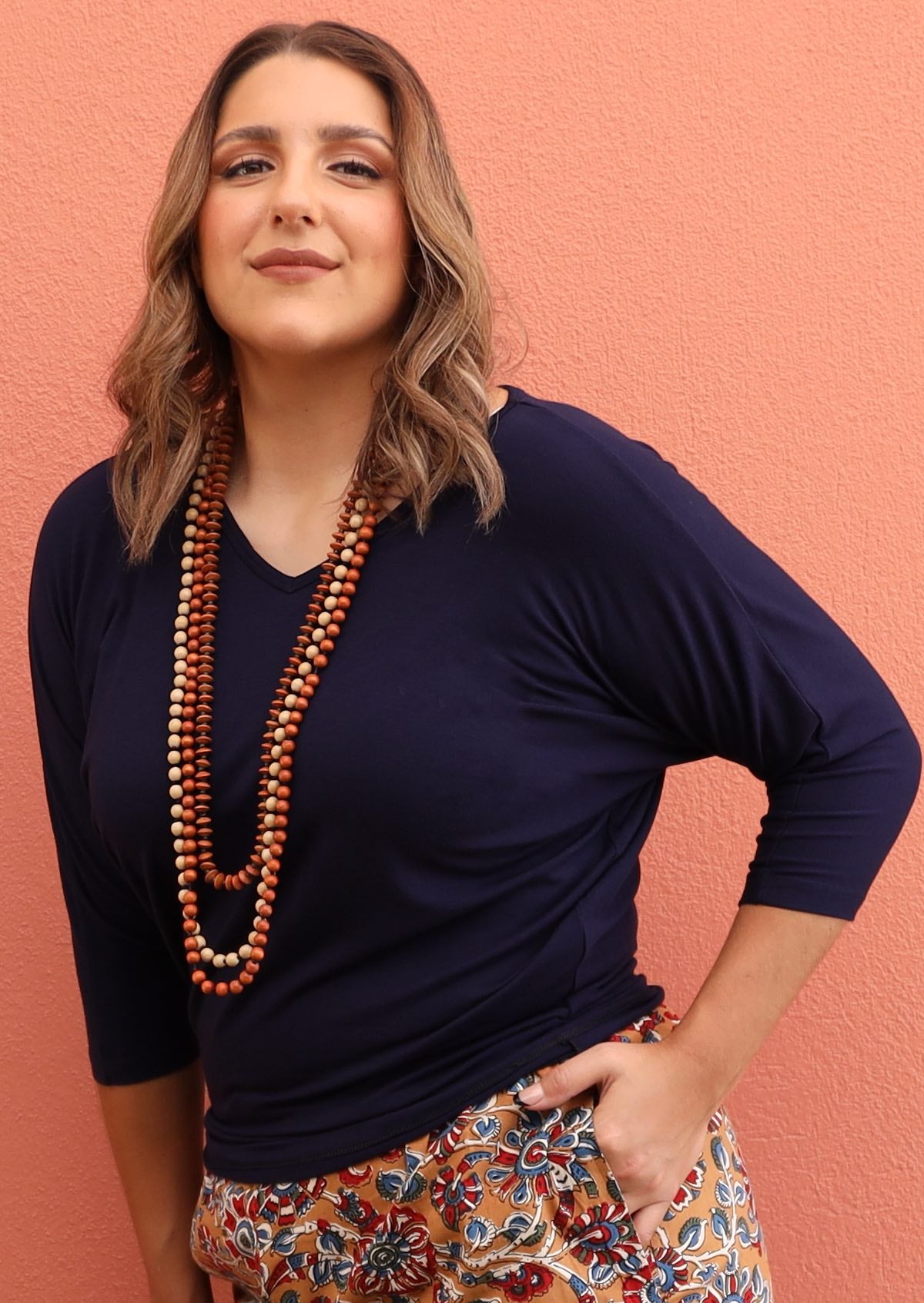 Woman wearing a 3/4 sleeve rayon batwing v-neck navy blue top.