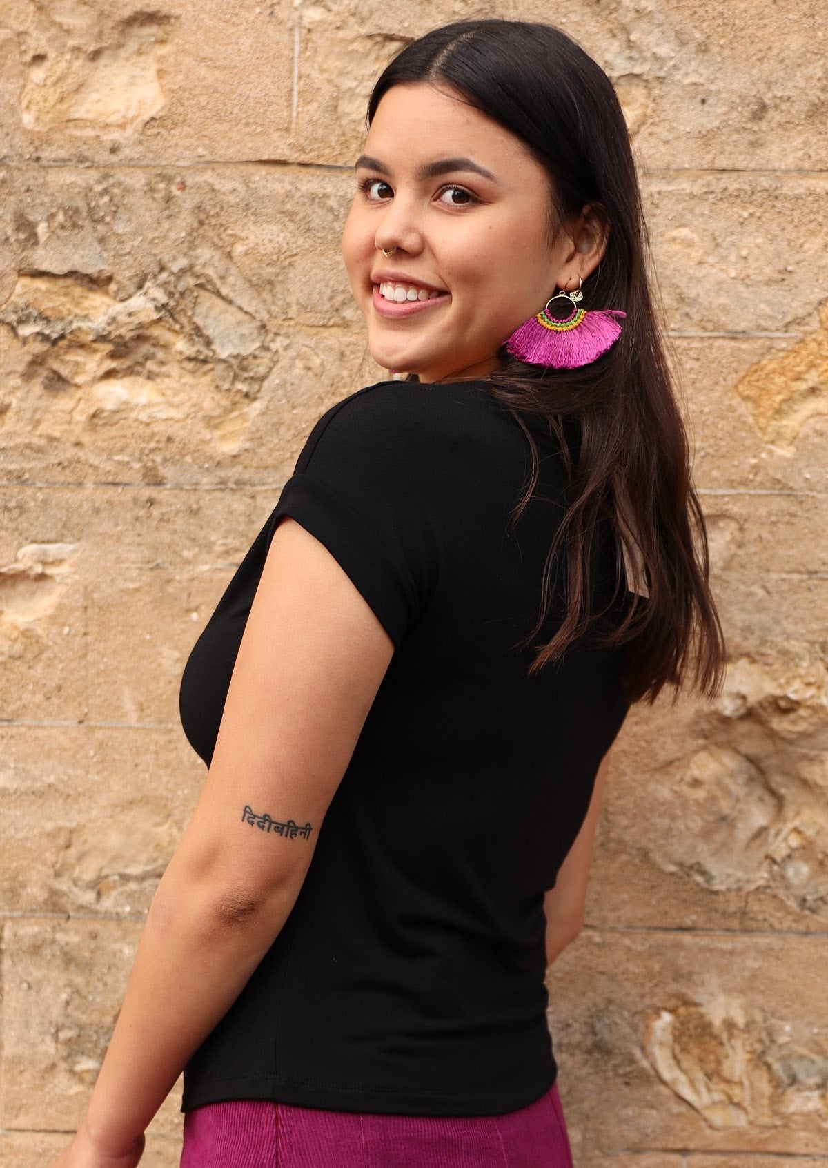Side view of woman wearing a wide neck mod black stretch rayon boat neck top with purple pants.
