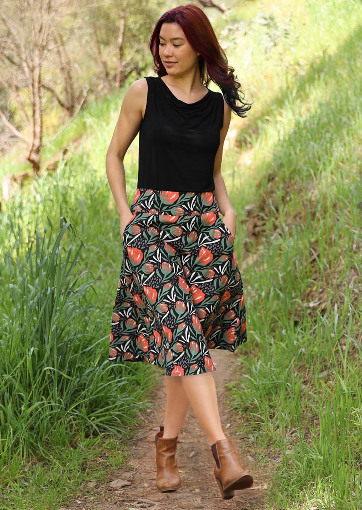 Model wears 100% cotton generous A-line skirt that sits over the knee with her hands in pockets on hips