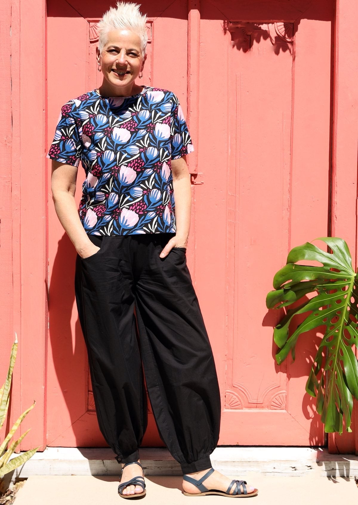 Woman wears lightweight black cotton relaxed fit pants with her hands in pockets