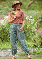 Acapulco Pants shirring across the back front wide flat waist band wide leg cuffed at ankle with button closure pockets 100% cotton light sage green background green and purple toned floral print | Karma East Australia