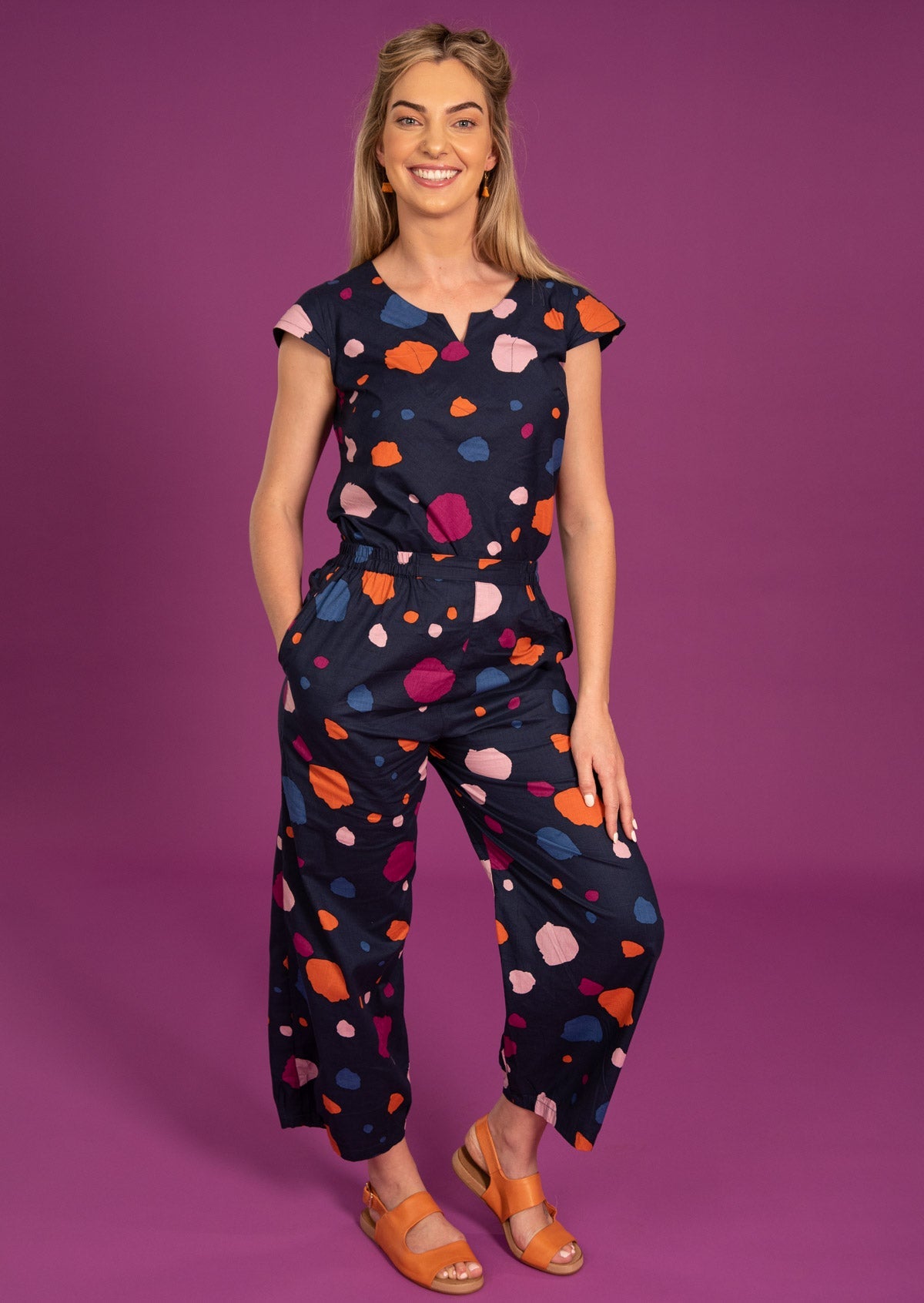 Woman wears spotty print on a blue base 100% cotton top and pant combo to give a jumpsuit appearance