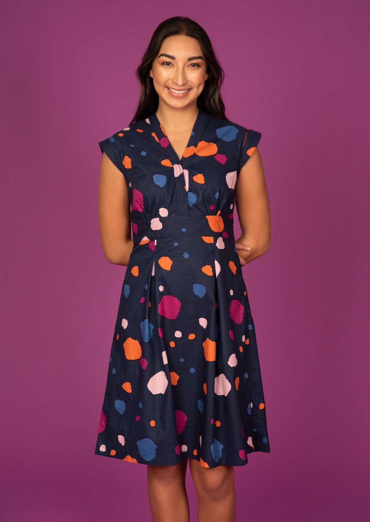 Woman wears 100% Cotton Bold Spotty Print Dress with tailored v-neckline, empire waistline, a-line skirt and side zipper