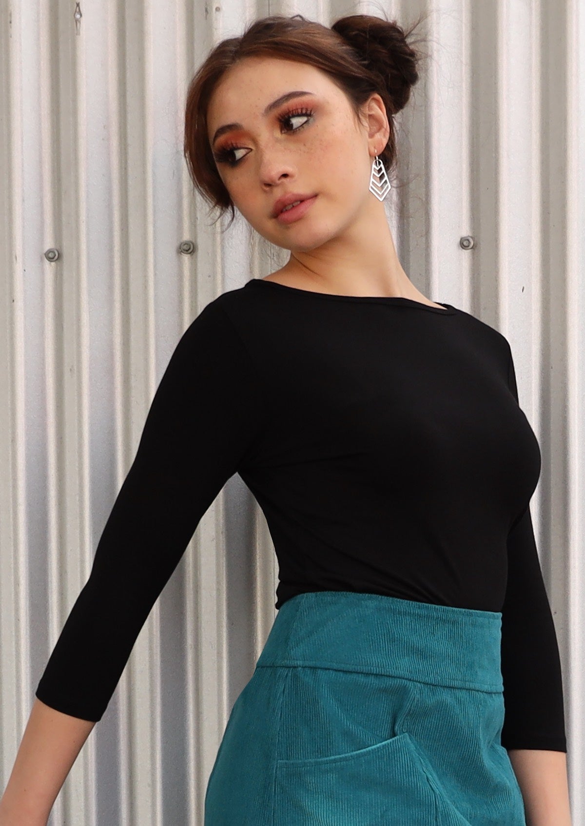 Woman with dark hair in two buns wearing a rayon boat neck black 3/4 sleeve top