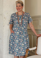 Woman wears floral print over the knee length cotton dress paired with wooden beaded necklaces