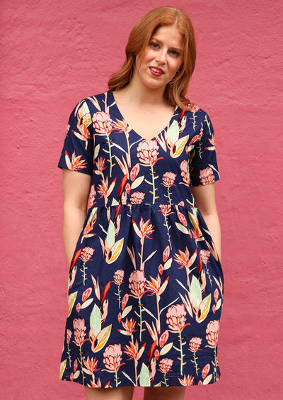 Model in V-neckline Dress Print navy background with pink and green toned native flowers