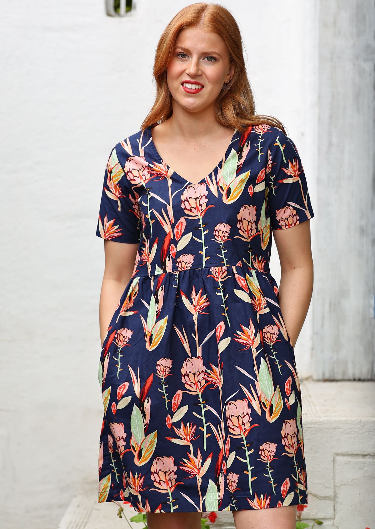 Redheaded model in a blue base with floral design v-neck dress with pockets   