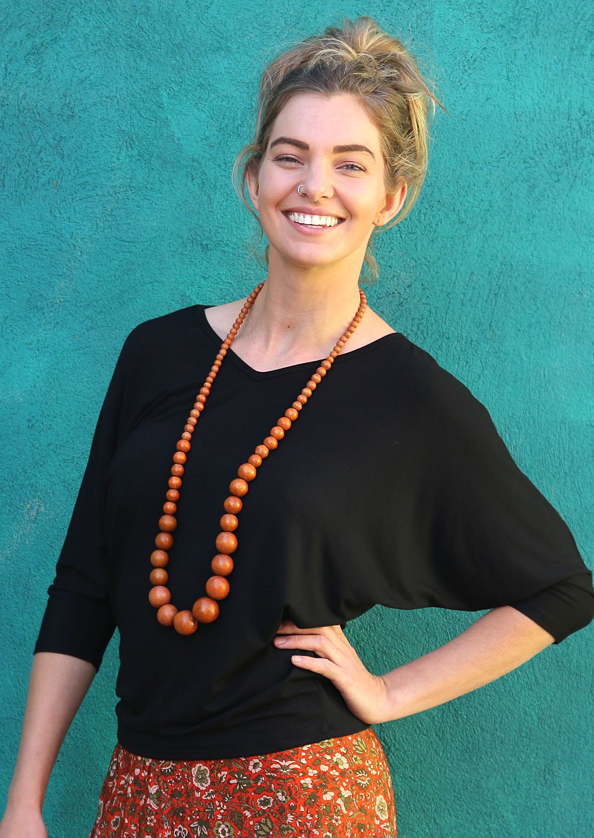 Woman with blonde hair wearing a 3/4 sleeve rayon batwing v-neck black top.