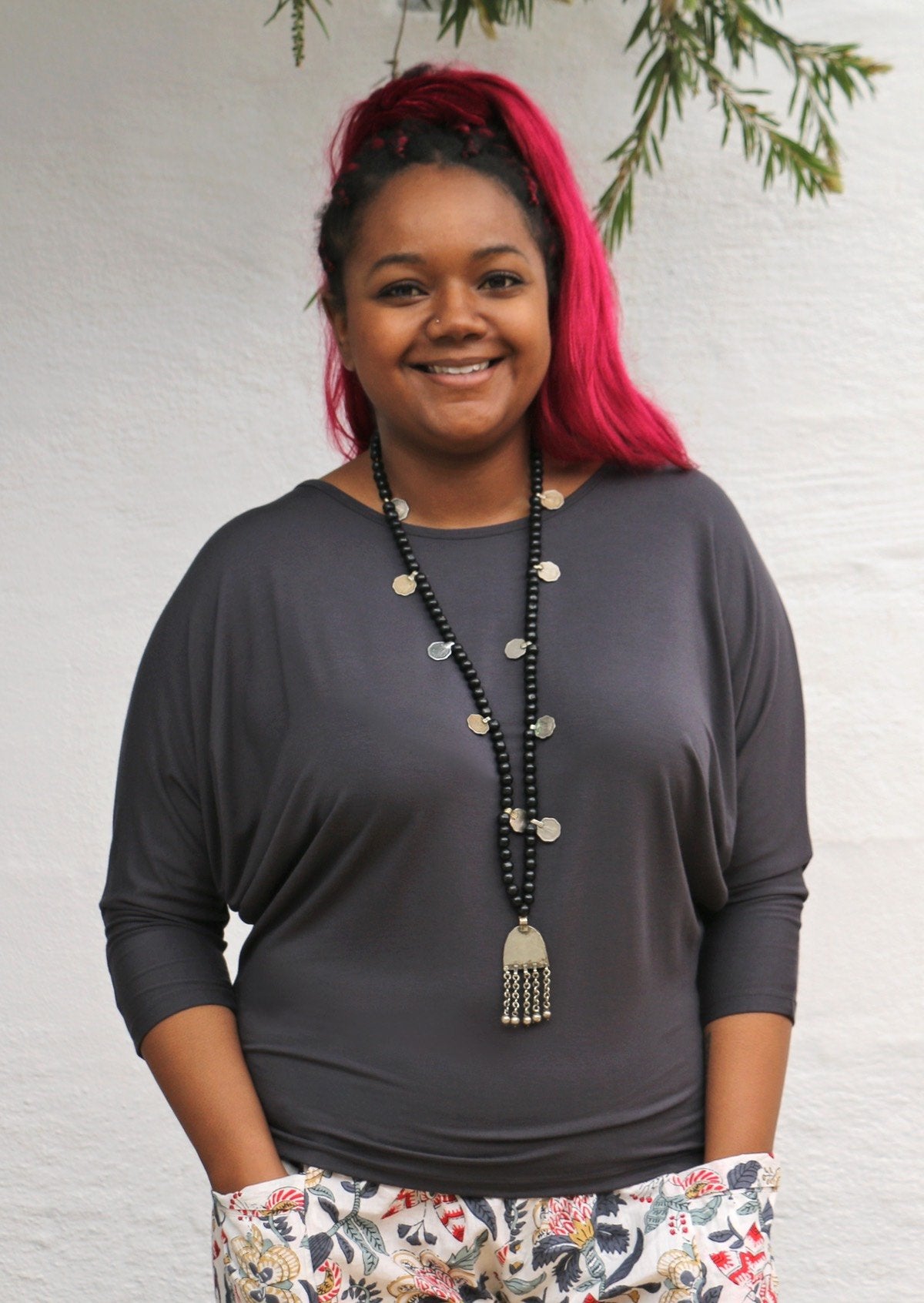 Woman with black and pink hair wearing a 3/4 sleeve rayon batwing round neckline dark grey top.