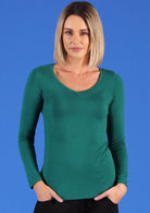Woman with a long blonde bob wearing a jade green long sleeve stretch v-neck soft rayon top.