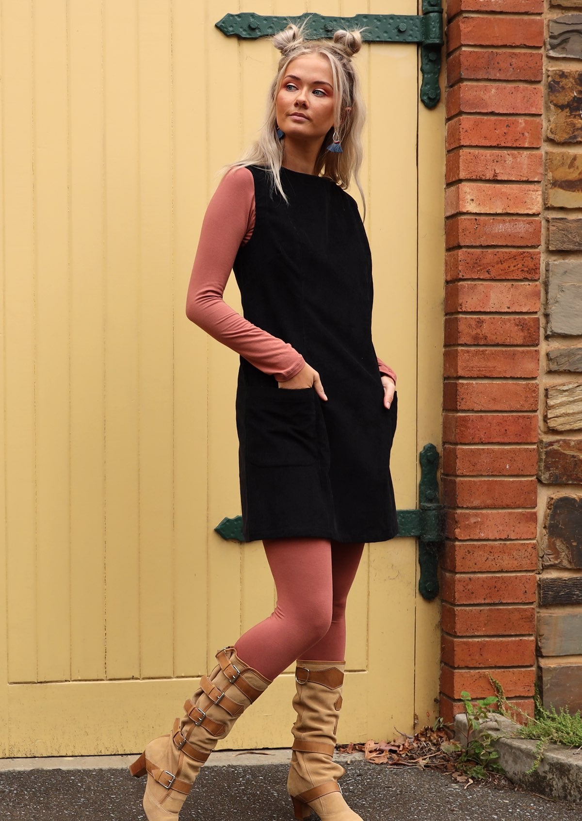 Woman wears retro style cotton corduroy tunic in black with long sleeve top and leggings in dusty pink underneath