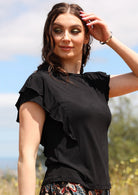 Woman wearing a black ruffle round neck short cap sleeve soft stretch rayon top.