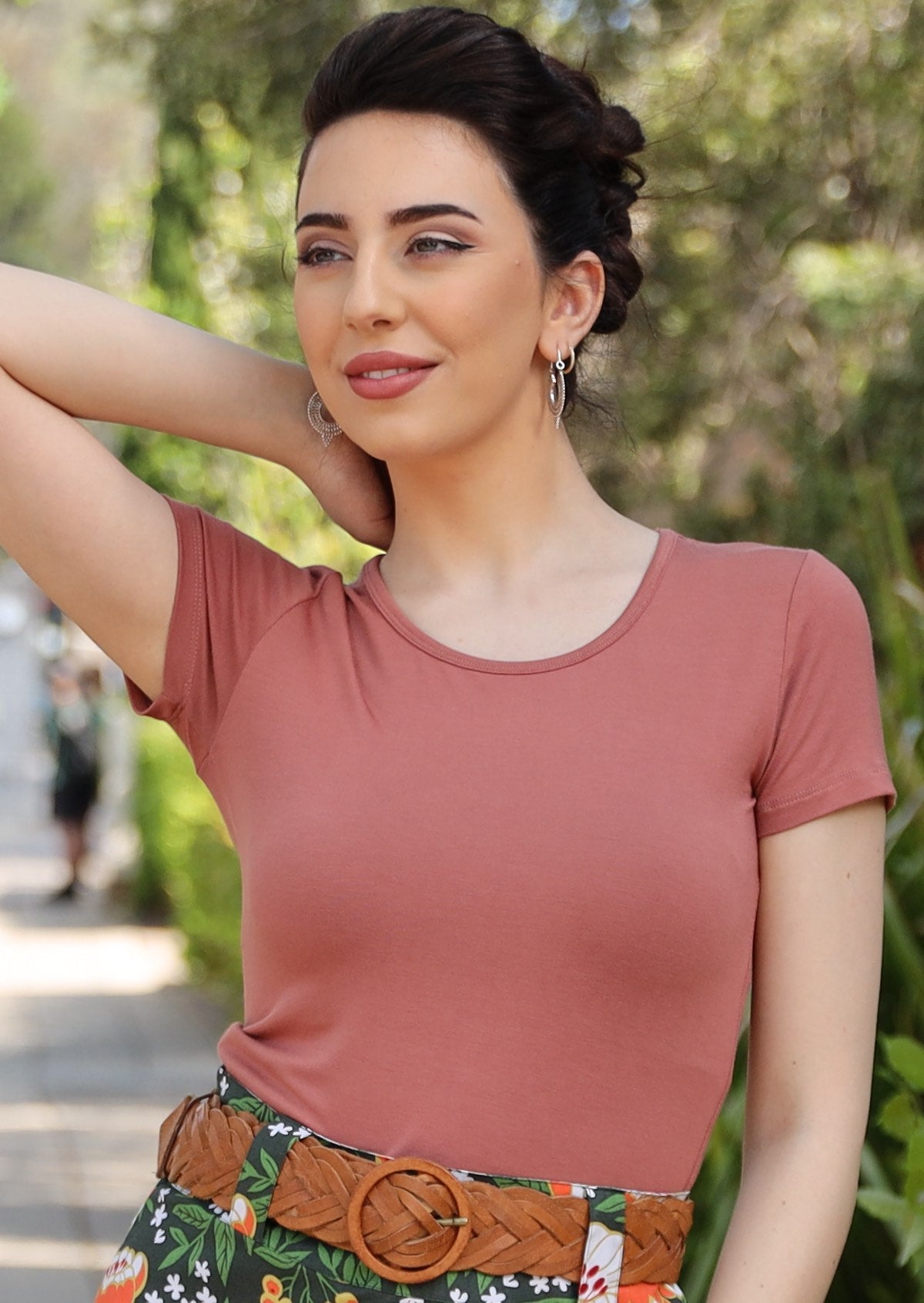 Woman wearing a scoop neck dusty pink rayon fitted t-shirt with tan belt and floral bottoms.