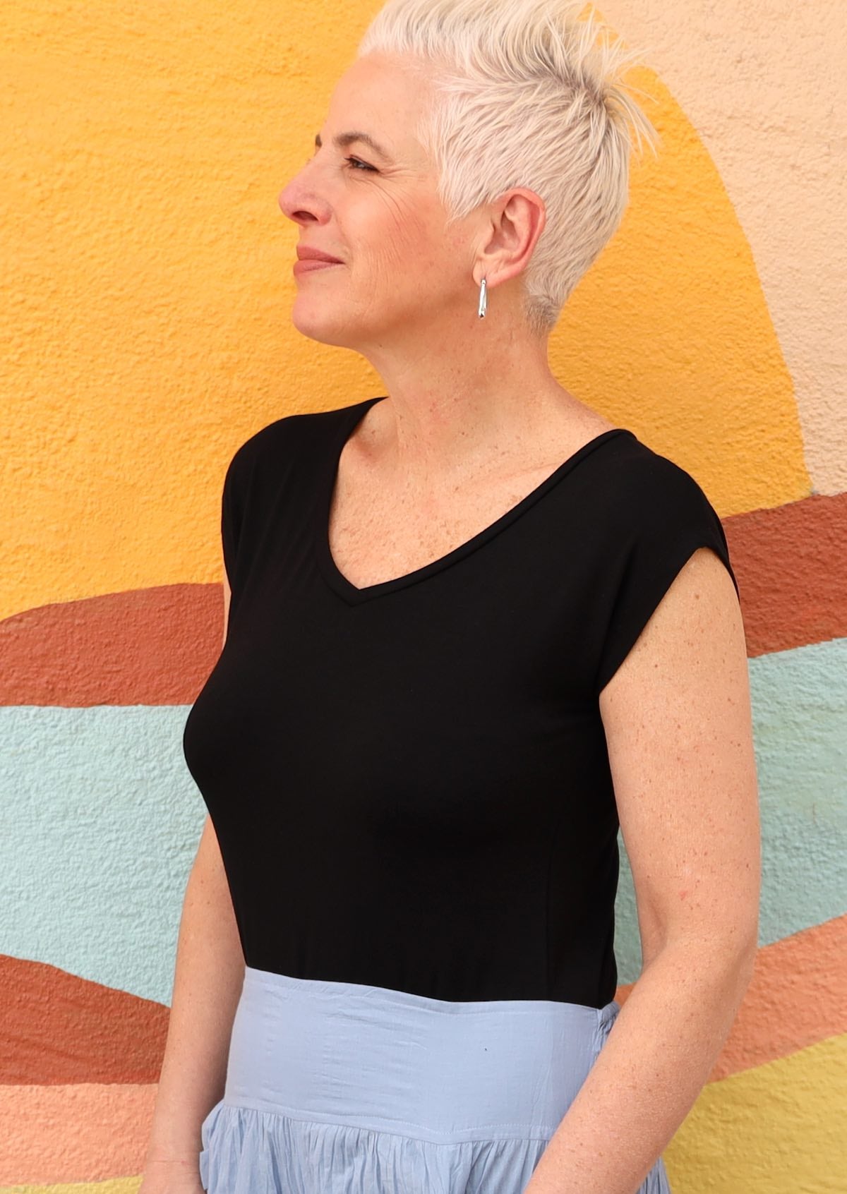 Woman wearing a black v-neck short cap sleeve rayon top with blue skirt.