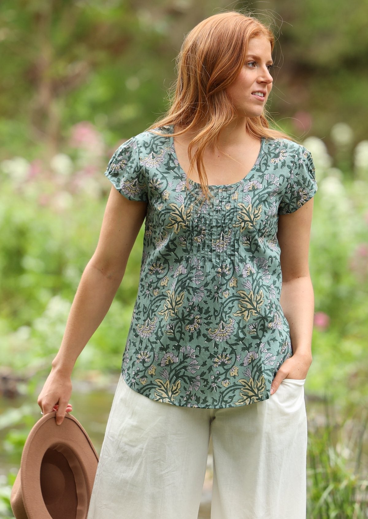 Woman wears relaxed fit cotton cap sleeved top in green floral print